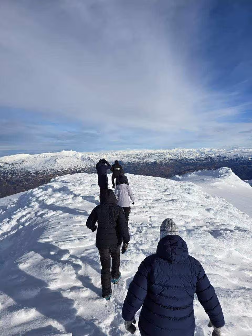 Group of hikers walking across snow-covered Eyjafjallajokull glacier with mountain panorama in Iceland