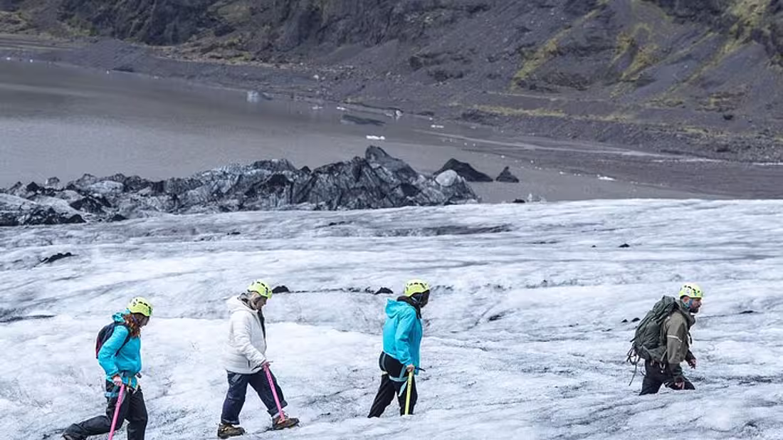 Group walking in a line hiking up a glacier in hiking gear