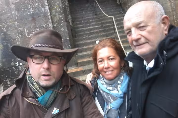 Three smiling tourists posing together at Mont-Saint-Michel stone walls during private guided tour
