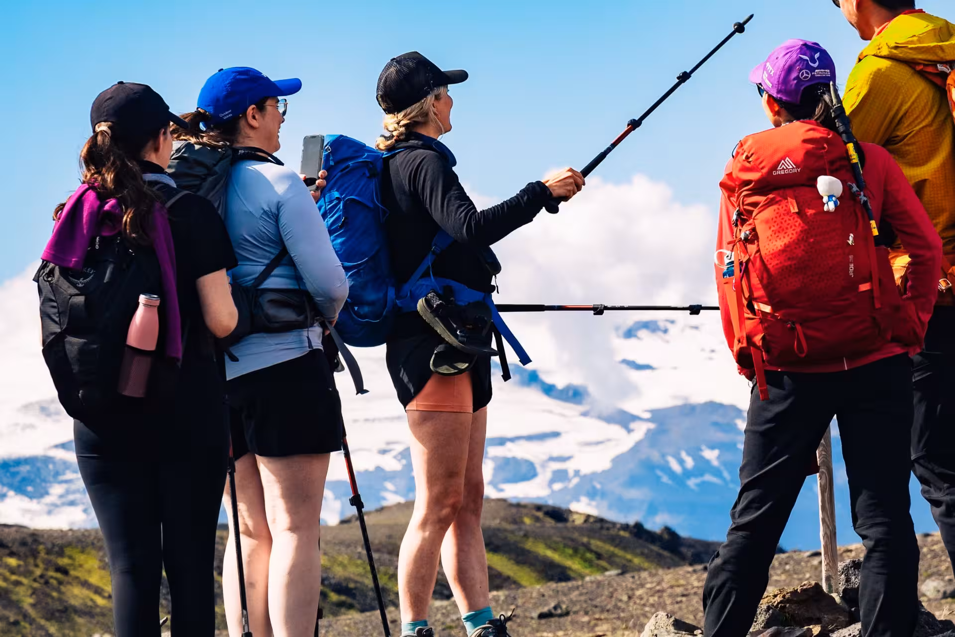 Group of hikers with trekking poles viewing snow-capped mountains on Laugavegur trail, Iceland