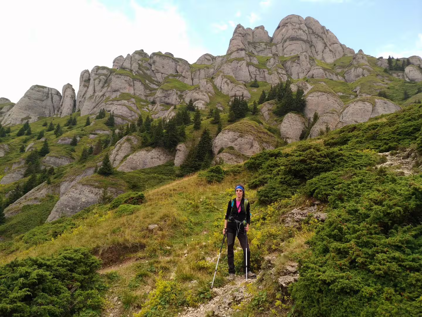 Female hiker with trekking poles on Ciucas Peak trail with dramatic rocky formations in Romania