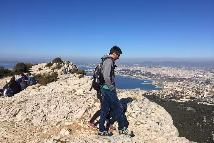 Guided hike viewpoint over Marseille, with hikers on limestone ridge above the sea and Calanques landscape