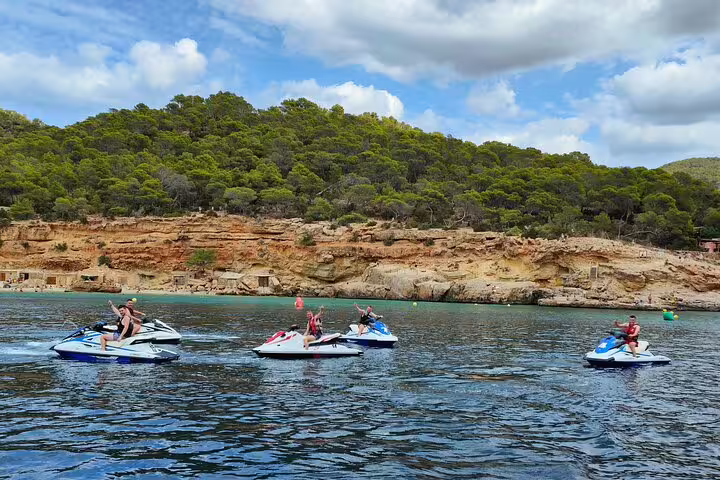 Group on jet skis cruising near Cala Salada Ibiza cliffs on a guided jet ski excursion in clear sea