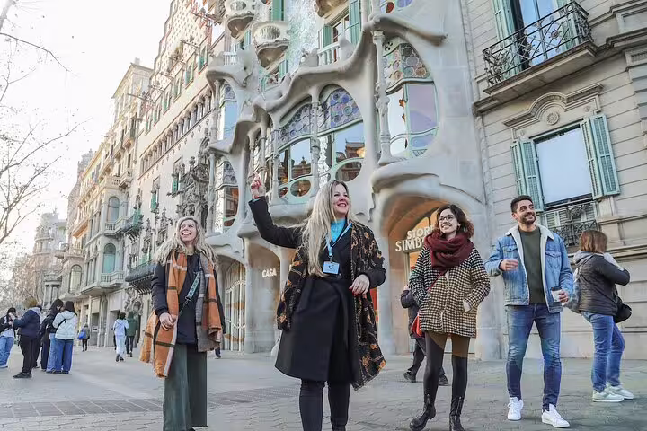 Guided morning walking tour group listening to guide outside Casa Batlló on Passeig de Gràcia in central Barcelona