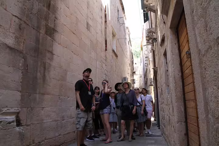 Guided Old Town walking tour group exploring a narrow stone alleyway inside the ancient city walls