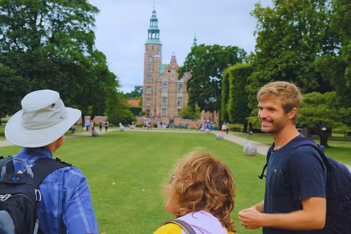Visitors enjoy a guided walk through the lush gardens leading to a historic castle in Copenhagen.