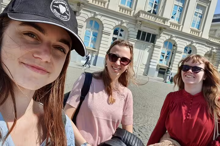 Three women smiling during a guided walking tour in Brussels city center on a sunny day