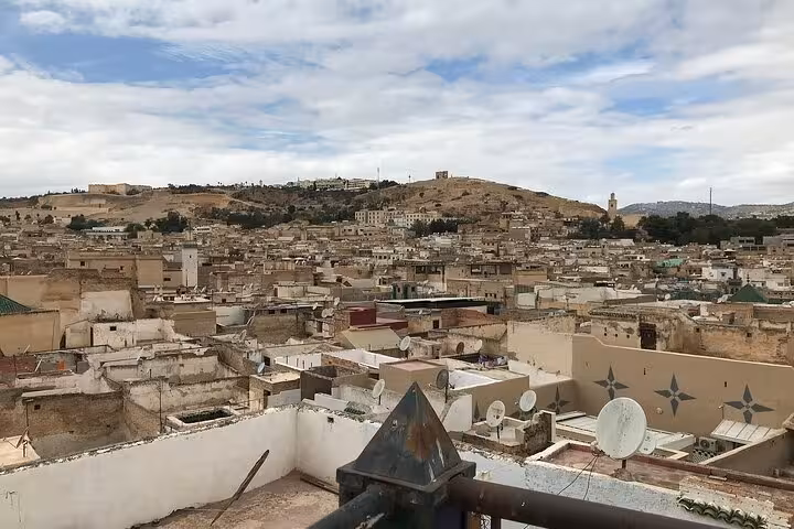 Panoramic view of Old Medina Fez showcasing traditional architecture under a partly cloudy sky on a guided walking tour.