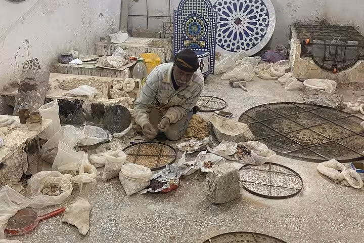 Artisan crafting traditional Moroccan mosaics during the Old Medina Fez walking tour experience.