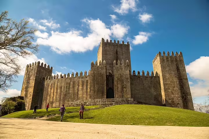 Discover the majestic medieval Guimarães Castle under blue skies on a captivating private tour from Porto.