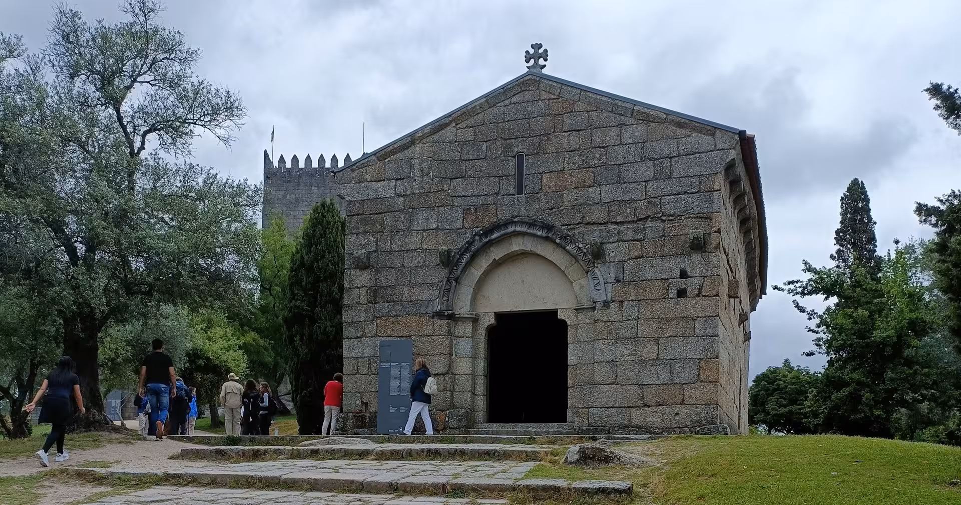 Romanesque chapel at Guimarães Castle grounds with visitors, part of Guimarães and Braga guided tour with lunch