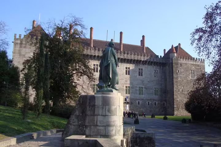 Explore the majestic Ducal Palace in Guimarães, featuring a prominent statue, on a curated half-day Porto tour.