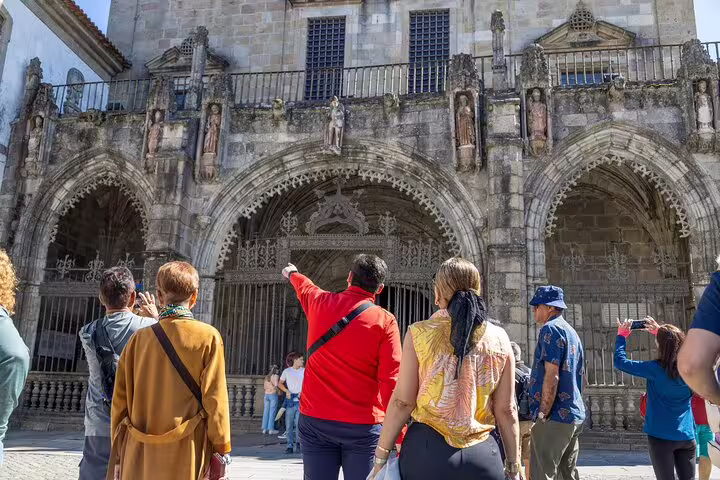 Visitors admire the Gothic architecture of Guimarães, capturing its intricate details during a guided tour.