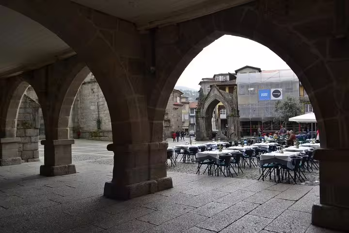 Charming Guimarães square with historic arches and outdoor cafe on a half-day private tour from Porto.
