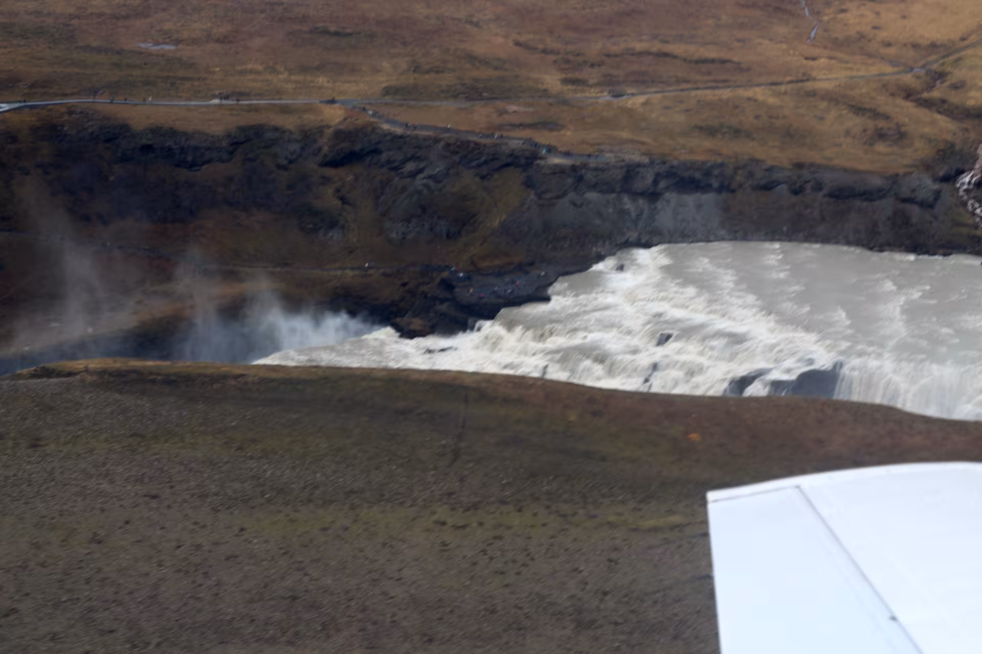 Aerial view of Gullfoss waterfall with mist rising, seen from airplane wing on Golden Circle tour