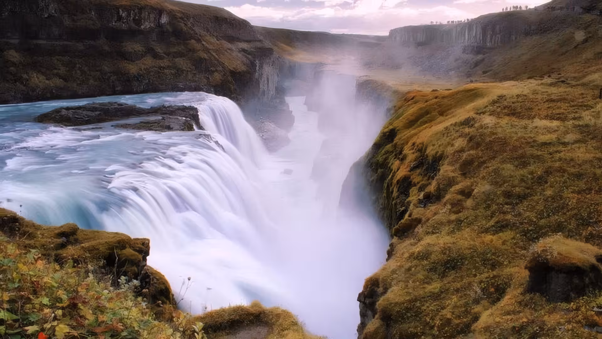 Gullfoss waterfall cascading into a misty canyon surrounded by mossy cliffs on Iceland's Golden Circle