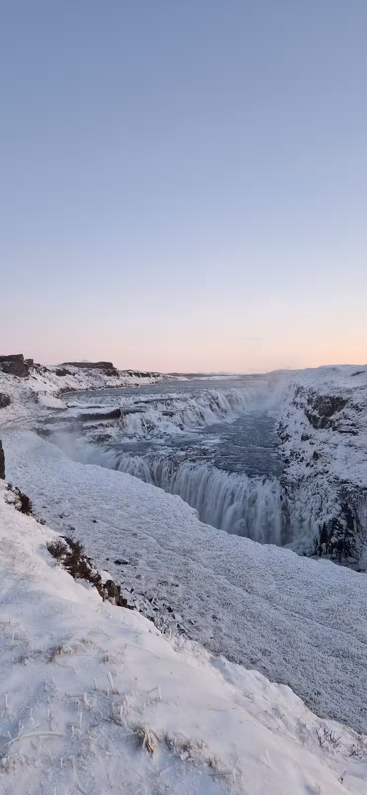 Snow-covered Gullfoss waterfall cascading into a misty gorge during a full-day private Golden Circle Iceland tour