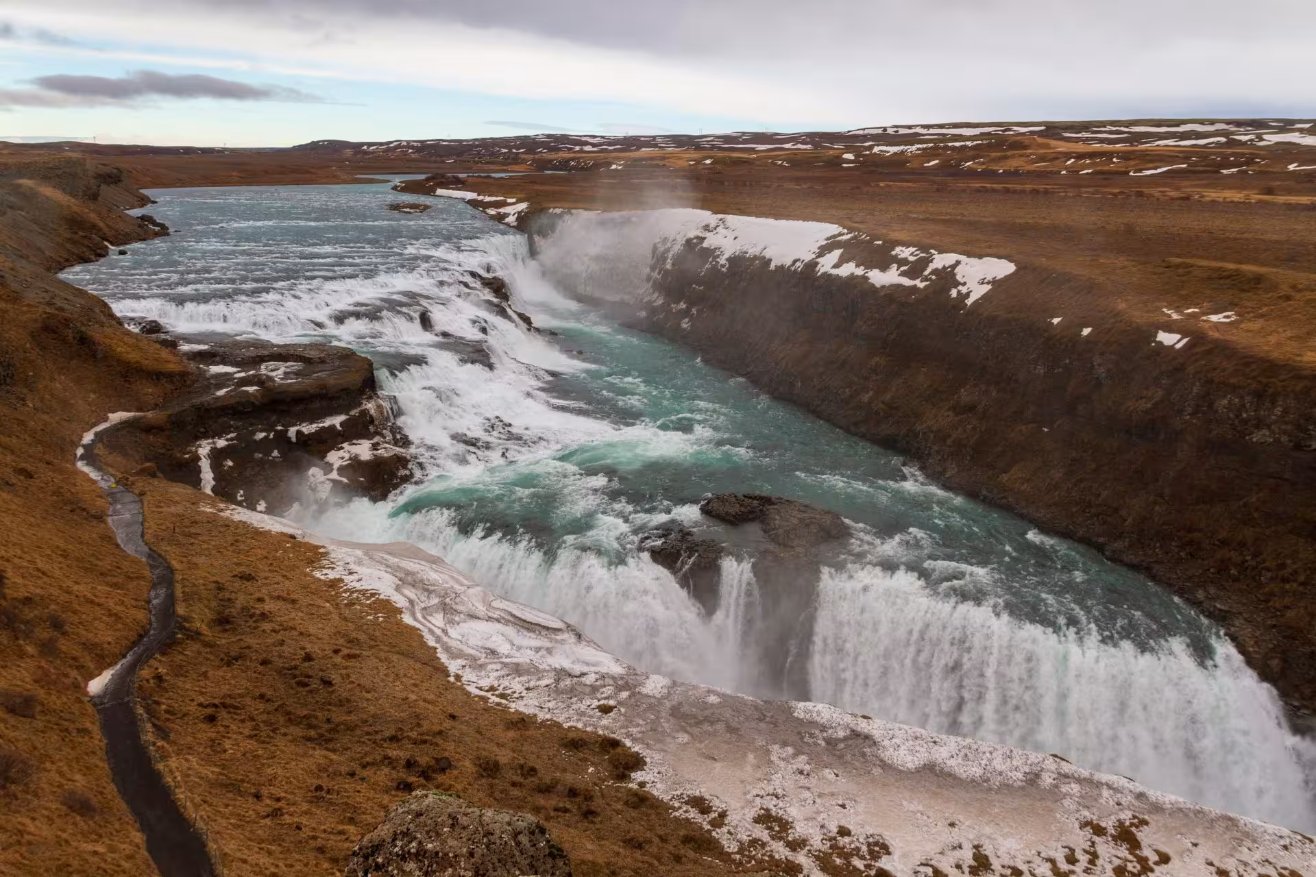Gullfoss waterfall cascading into a glacial canyon with snow-dusted cliffs on Iceland's Golden Circle route