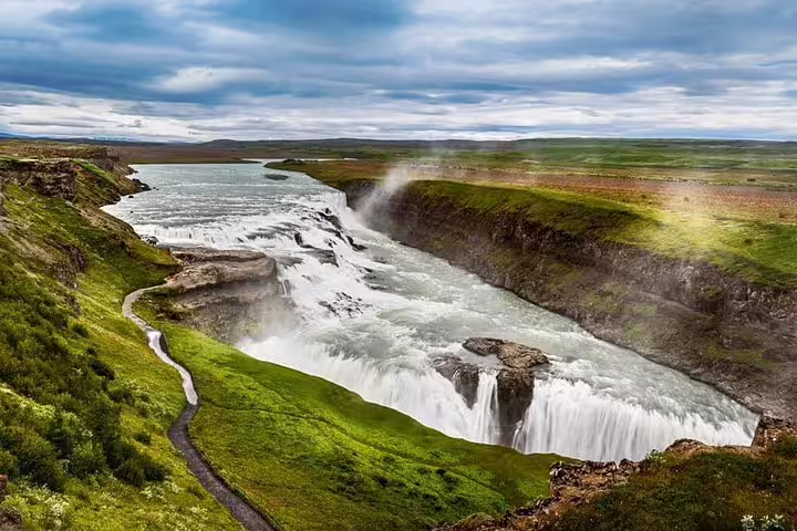 Gullfoss waterfall cascading into a canyon surrounded by green Icelandic landscape on the Golden Circle
