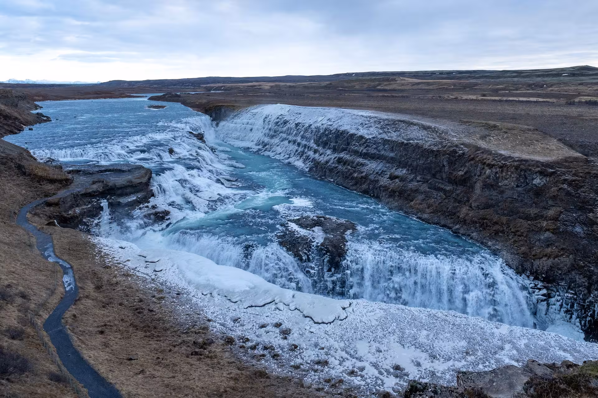 Gullfoss waterfall on Iceland's Golden Circle with cascading tiers, turquoise glacial water, and winter ice formations