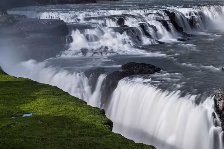 Gullfoss waterfall cascading over rocky cliffs with lush green mossy banks, Iceland Golden Circle
