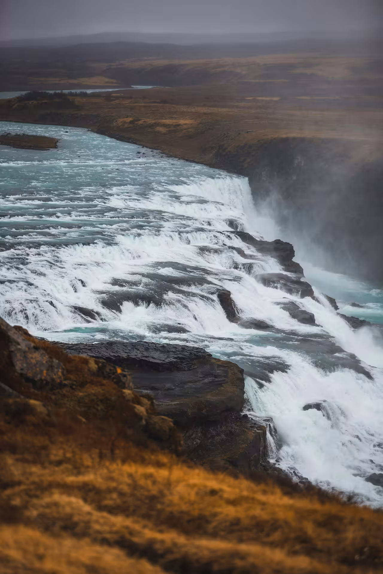 Gullfoss waterfall cascading over rocky ledges in Iceland on a dramatic overcast day
