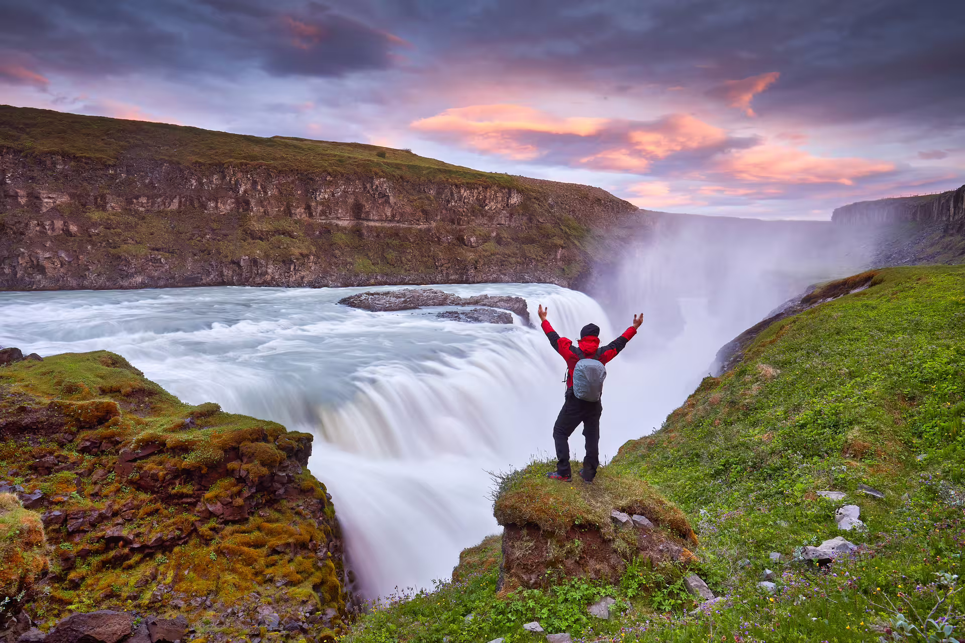 Hiker with arms raised at Gullfoss waterfall on Iceland's Golden Circle at sunset