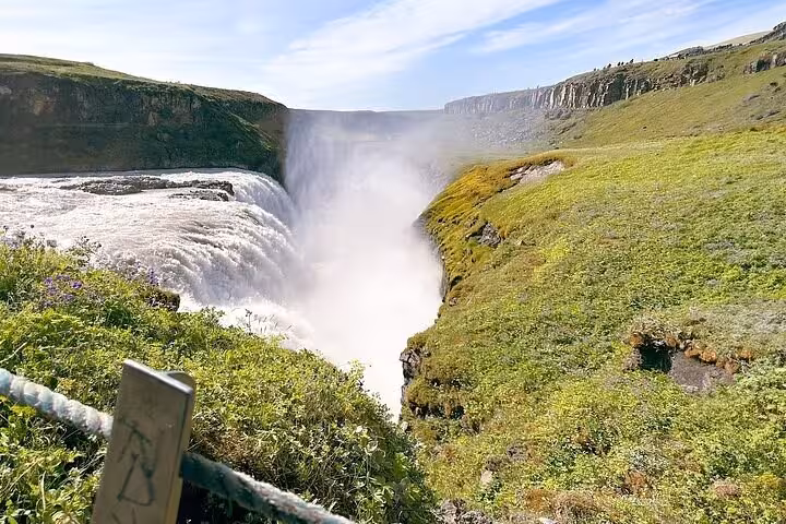 Gullfoss waterfall cascading into canyon surrounded by green landscape on Iceland's Golden Circle