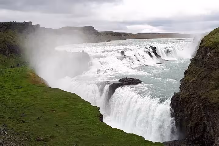 Gullfoss waterfall cascading into canyon on Iceland's Golden Circle with mist rising over green cliffs