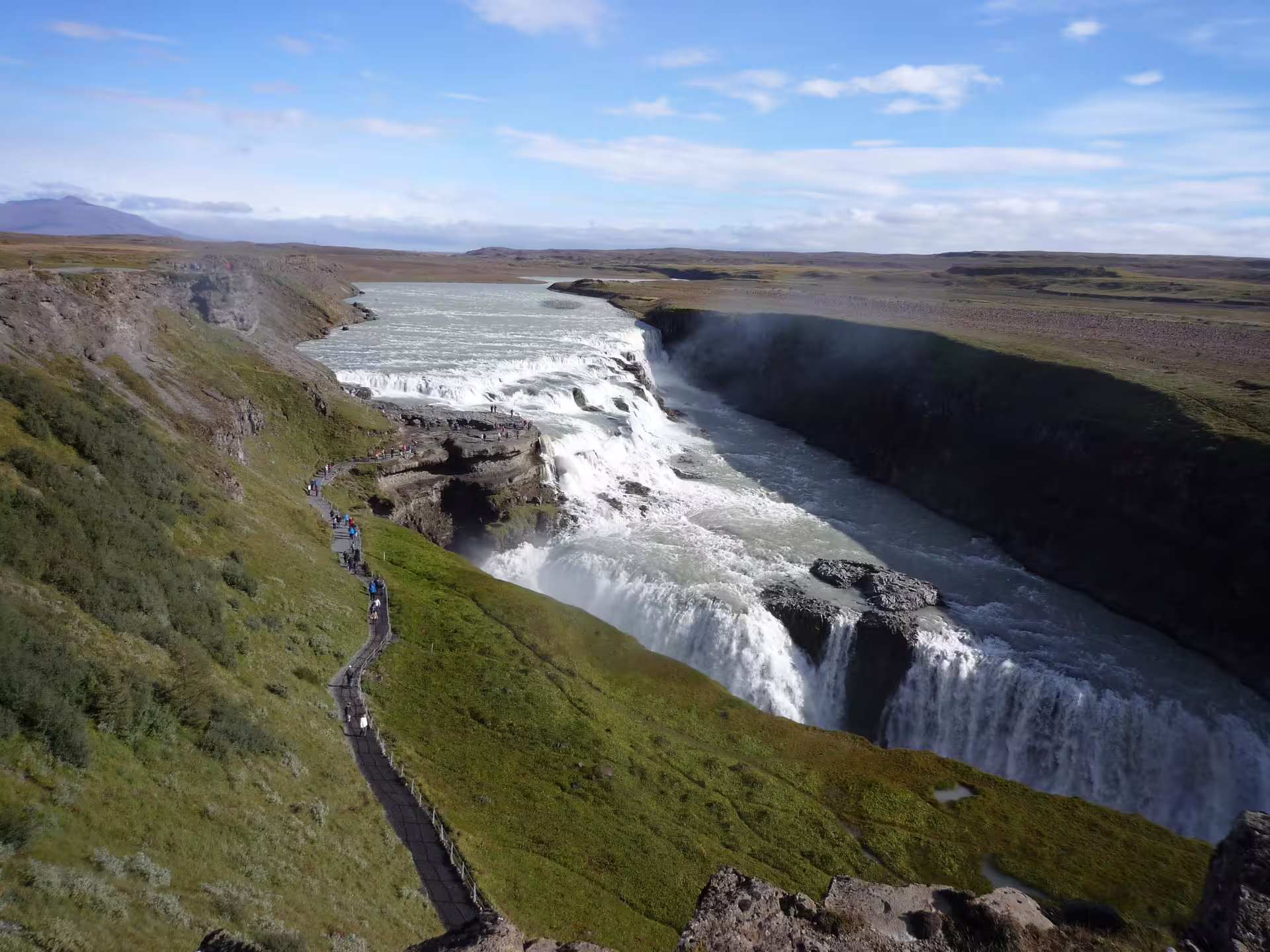 Aerial view of Gullfoss waterfall cascading into a canyon on Iceland's Golden Circle route with tourists on viewing path