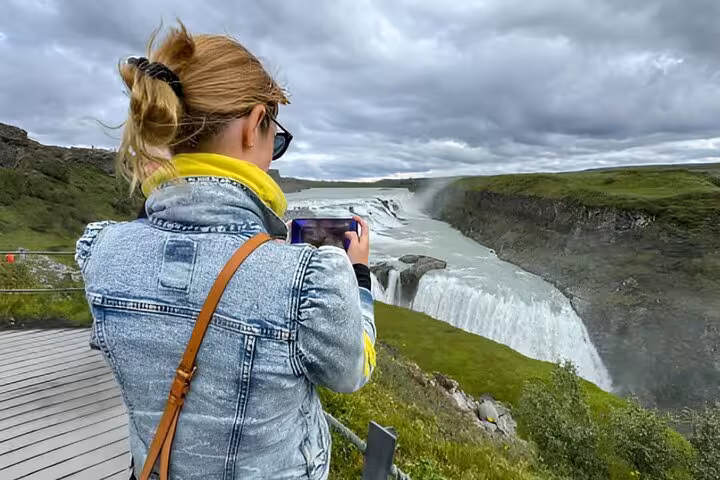 Tourist photographing Gullfoss waterfall on Golden Circle tour from Keflavik Airport