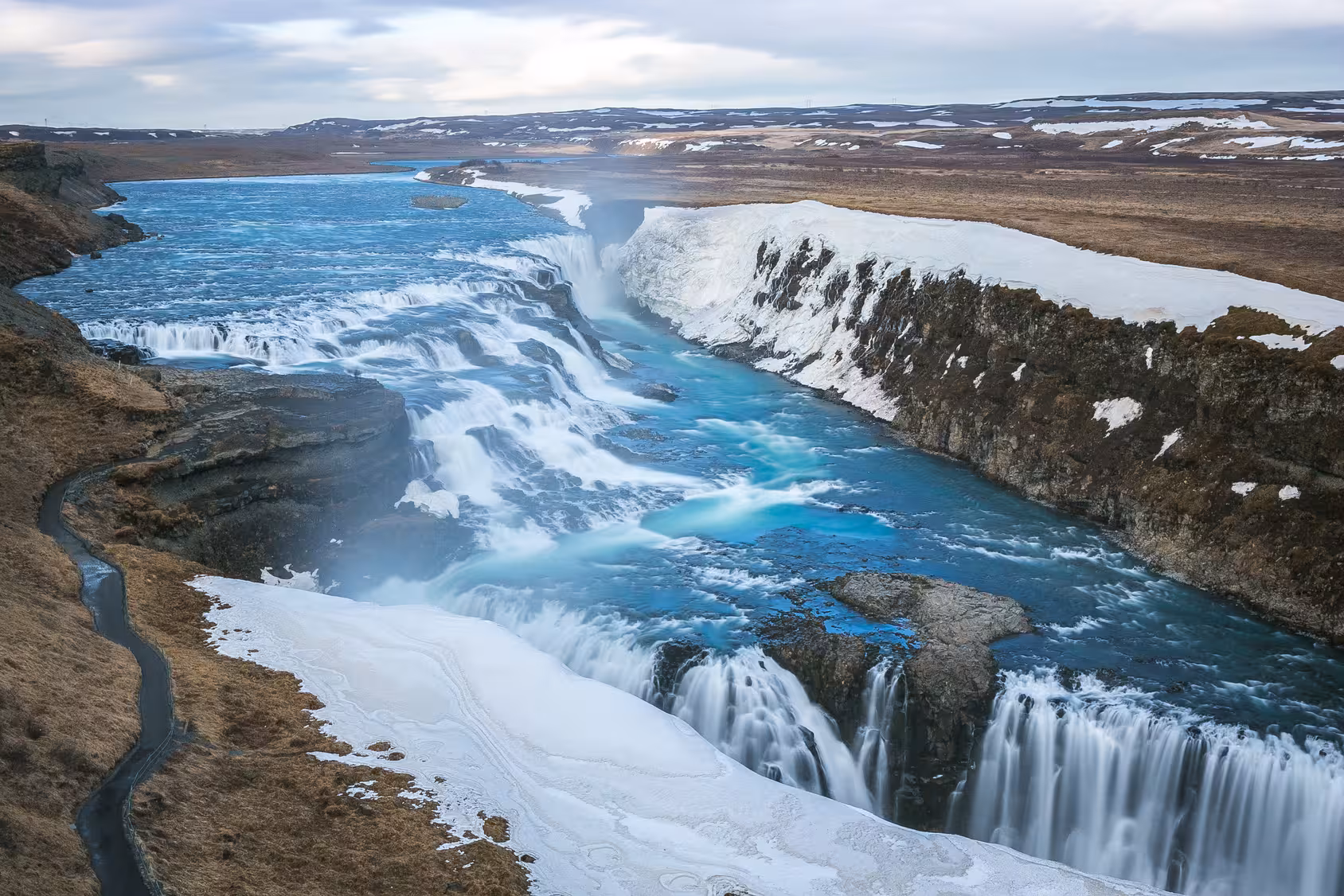 Majestic Gullfoss Waterfall cascading through rugged Icelandic landscape on a 6-day stopover tour.