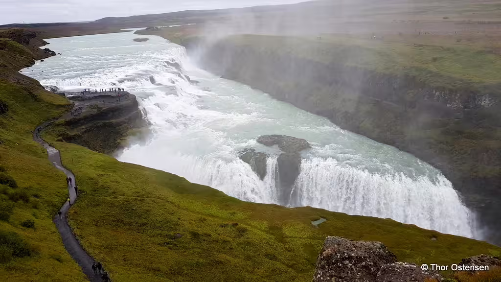 Gullfoss waterfall cascading into a canyon with green cliffs and mist, Iceland Ring Road tour highlight