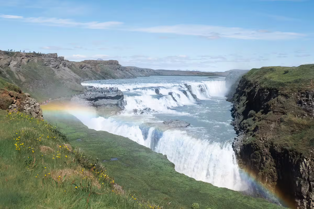 Gullfoss waterfall with rainbow mist on Iceland's Golden Circle tour, cascading into a rocky canyon