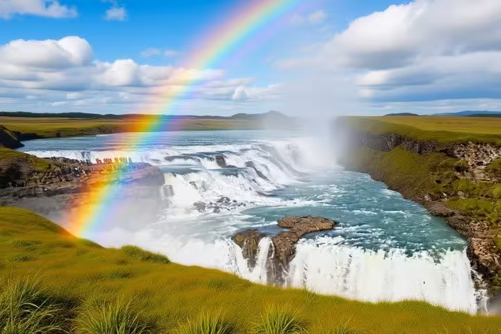 Rainbow over Gullfoss waterfall with turquoise water and green landscape on Iceland's Golden Circle