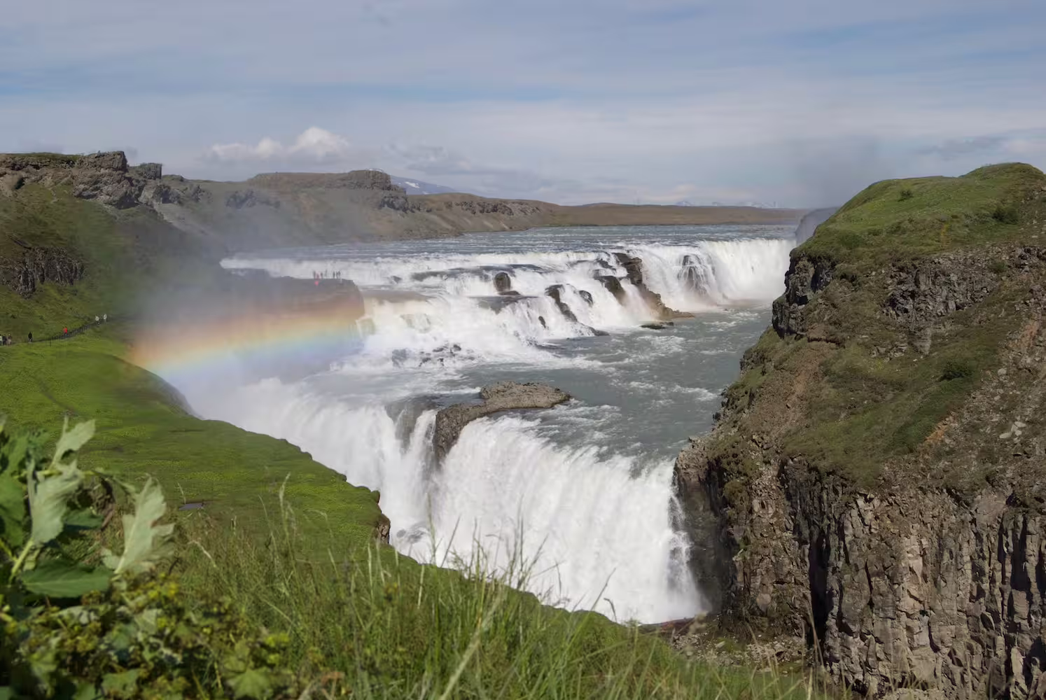 Gullfoss waterfall with rainbow and green cliffs in Iceland summer landscape