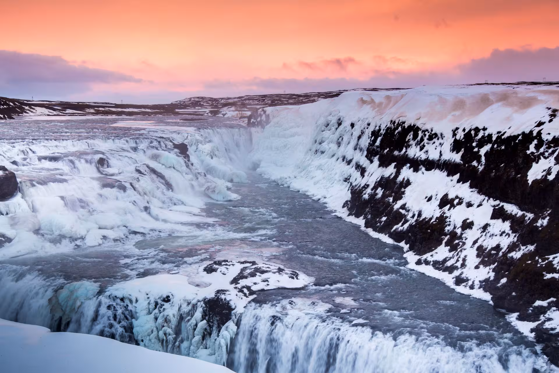 Gullfoss waterfall in winter with snow-covered canyon and pink sunset sky, Iceland Golden Circle