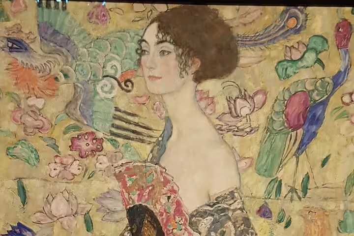 Close-up of a colorful Gustav Klimt painting featuring a woman surrounded by intricate floral and bird designs.