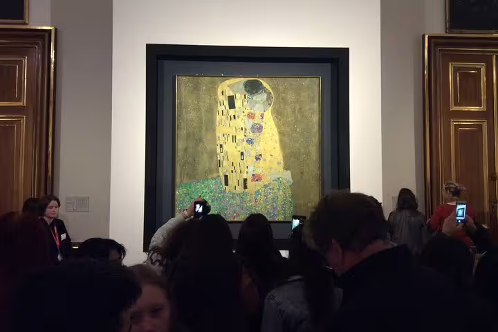 Crowd viewing Gustav Klimt's iconic 'The Kiss' at Belvedere Museum, showcasing vibrant Vienna art tour.