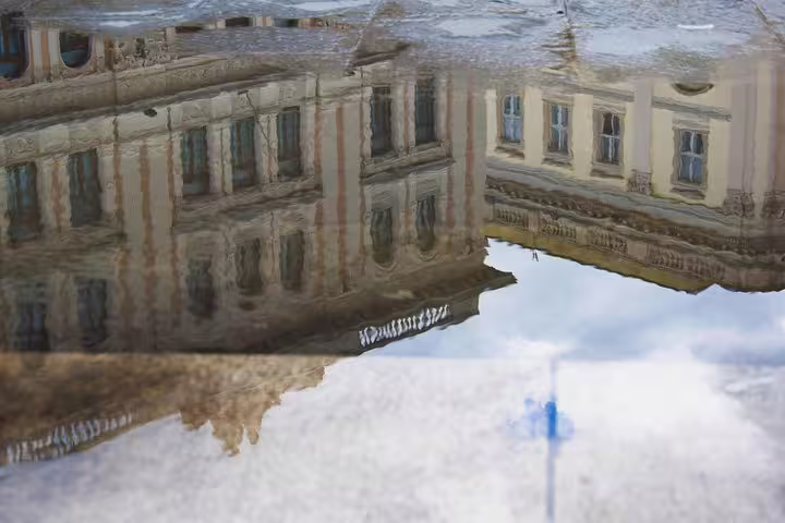 Reflection of ornate Habsburg Trieste palaces in a rain puddle, seen on a historic private walking tour of the city