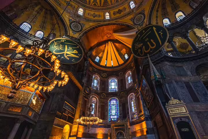 Interior of Hagia Sophia with intricate golden mosaics and grand chandeliers, showcasing Istanbul's rich history.