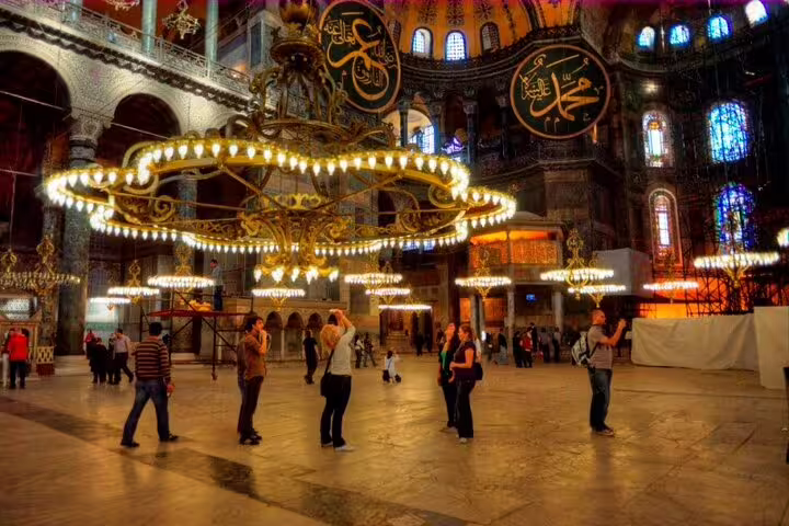 Hagia Sophia interior in Istanbul with grand chandelier, mosaics and visitors on guided small group tour