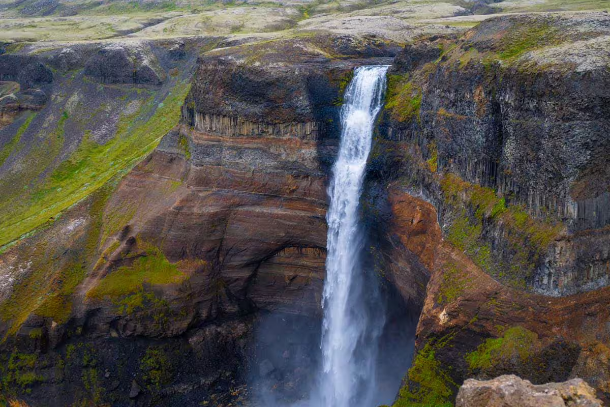Haifoss waterfall plunging into a deep canyon with layered volcanic rock walls and green moss in Landmannalaugar