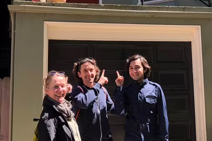 Three smiling people posing in front of a garage door in Haight-Ashbury, San Francisco