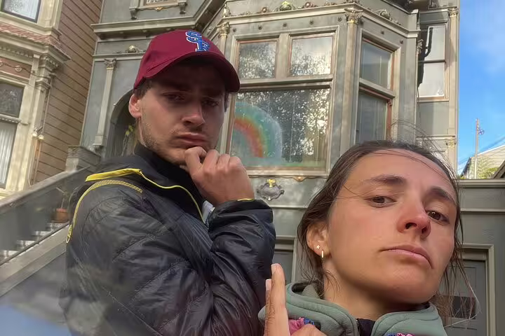 Two visitors posing in front of a Victorian house in Haight-Ashbury, San Francisco