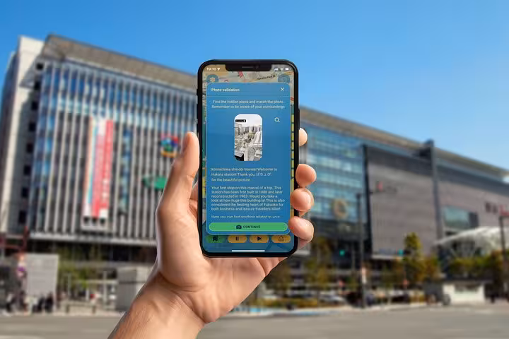 Self-guided GPS city explorer app showing photo validation challenge at iconic Hakata Station in Fukuoka