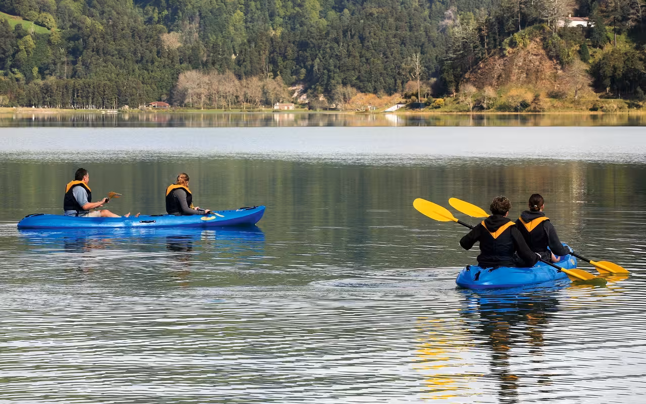 Half-day canoeing tour on a calm forest lake, paddlers in blue kayaks with life jackets and yellow paddles