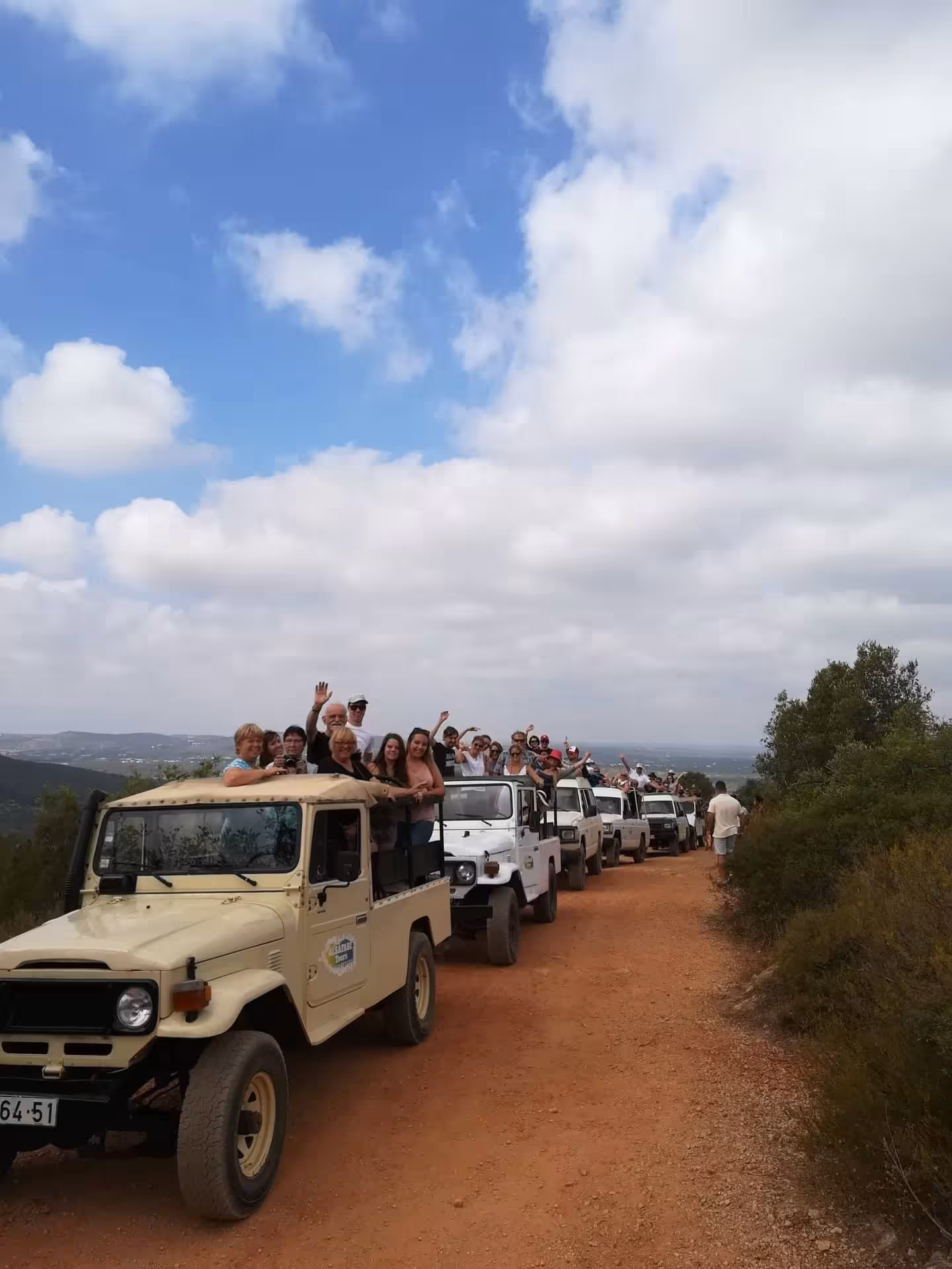 Convoy of open-top jeeps filled with tourists on a dusty Algarve trail during a guided Half Day Jeep Safari adventure