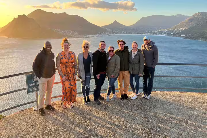 Tour group posing with stunning coastal backdrop at sunset on Half Day Penguins and Cape of Good Hope Tour.