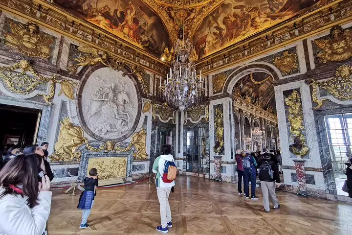 Visitors explore the grand Hall of Mirrors at Versailles on a private full-day Giverny and Versailles tour